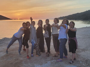 Gruppenfoto am Strand bei Sonnenuntergang.