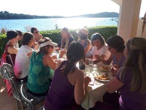 Bild zeigt 10 Personen am Tisch essend, mit Blick aufs Meer.