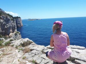 Bild zeigt sitzende Frau, die zum Meer blickt.